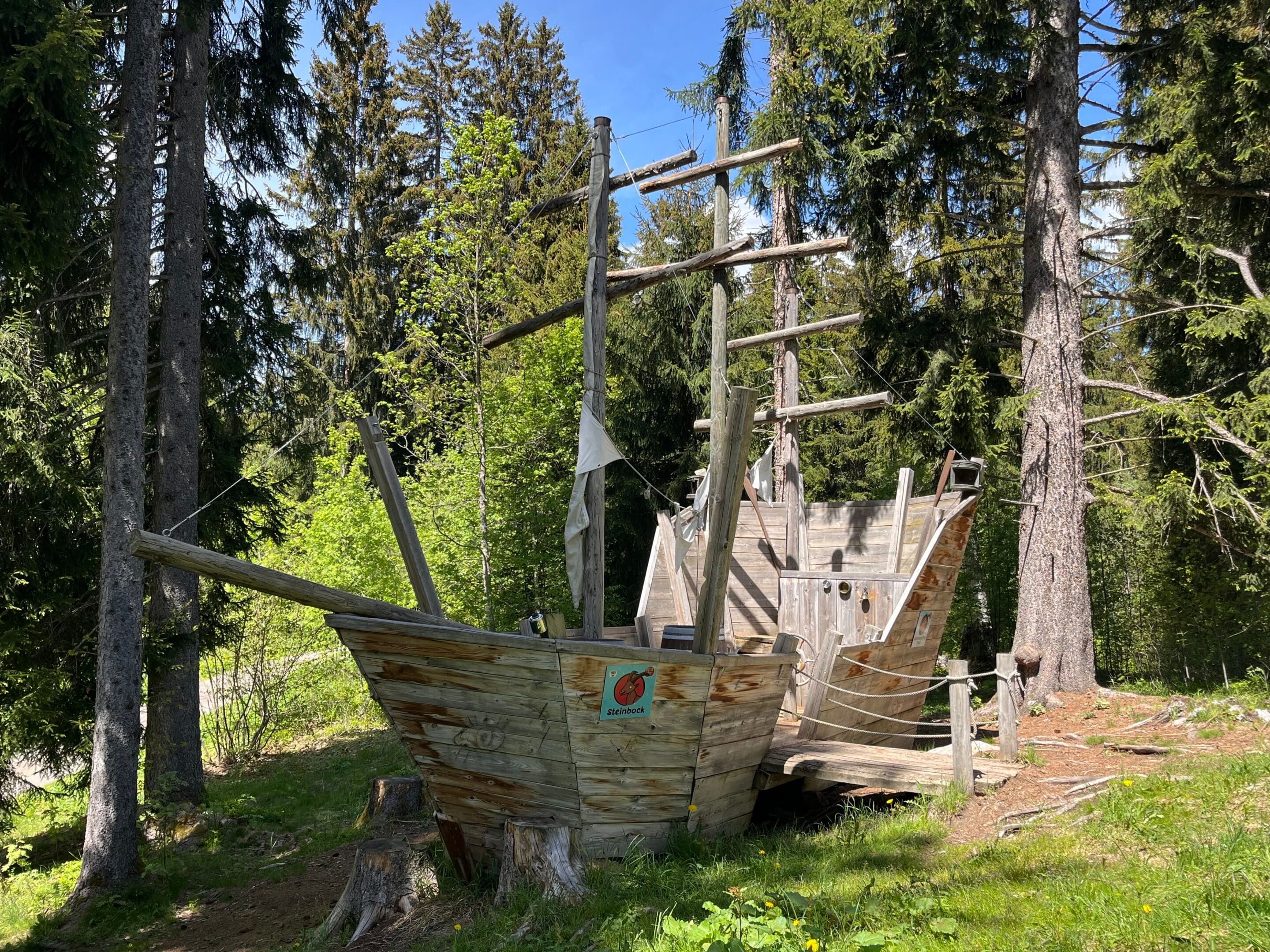 Feuerstelle mit Holzkonstruktion und Spielplatz im Wald