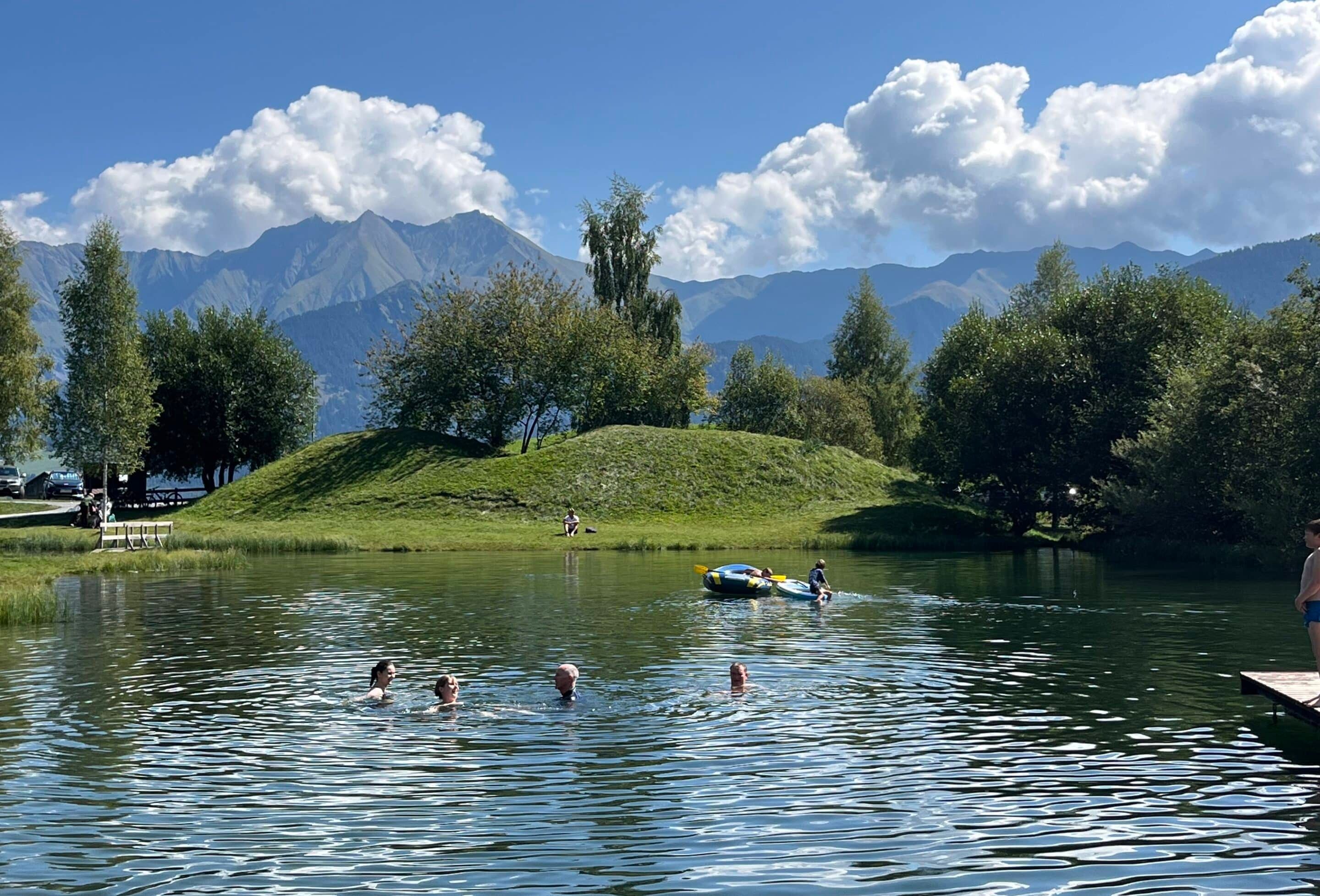 Bergsee mit Badenden vor eindrucksvoller Bergkulisse